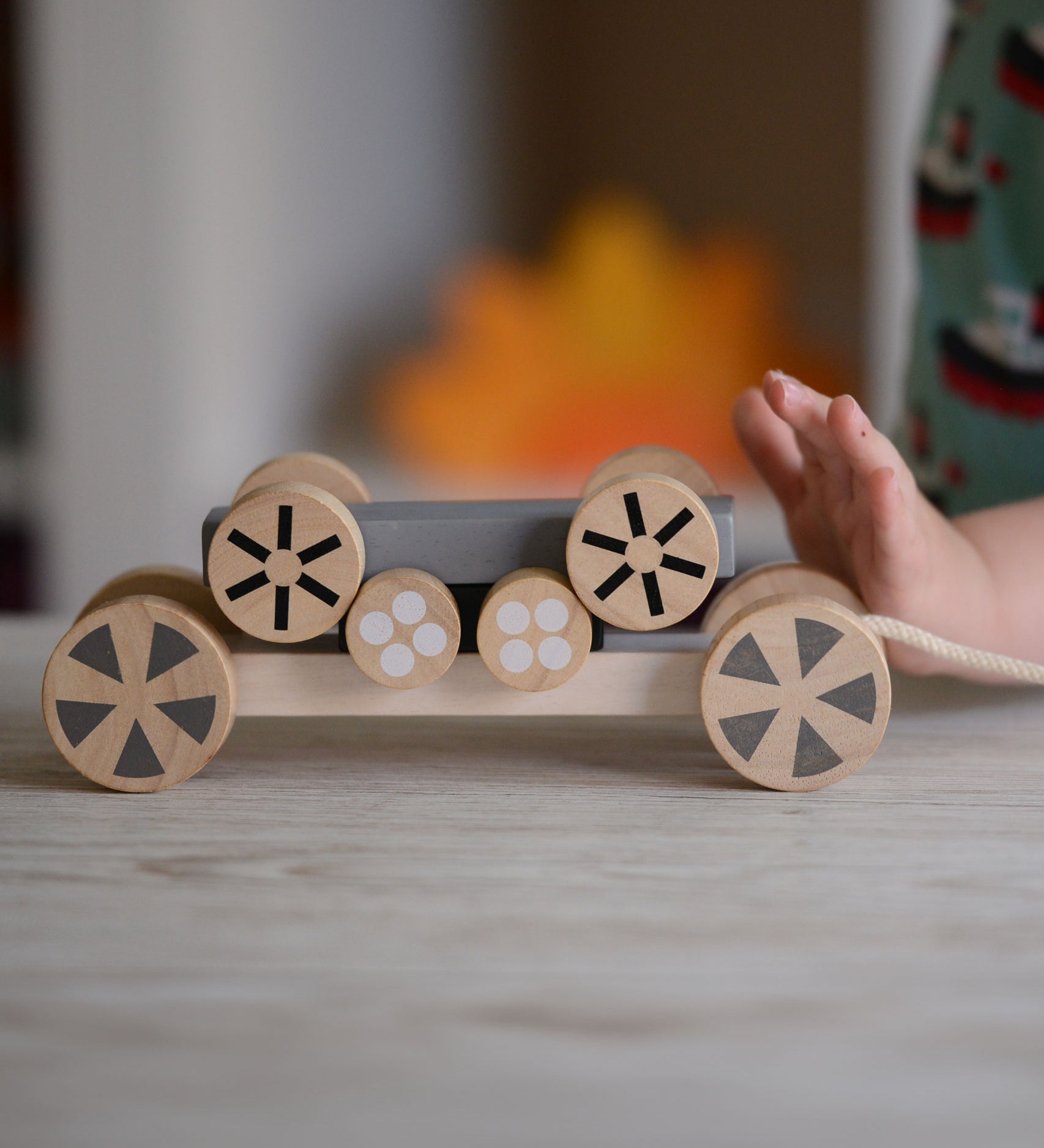 The Plan Toys Stacking Wheels toy, a child's hand can be seen on the side pushing the wheels.