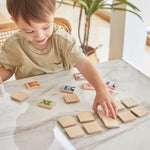 A young boy sat at a white marble table playing with the PlanToys wooden animal memory game. 