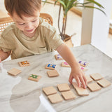 A young boy sat at a white marble table playing with the PlanToys wooden animal memory game. 