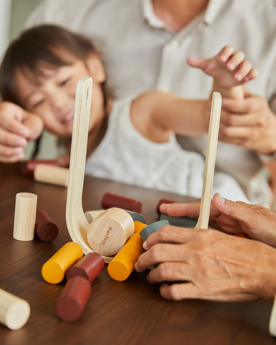 woman and young girl sat at a table playing with the PlanToys plastic-free wooden beaver tumble game