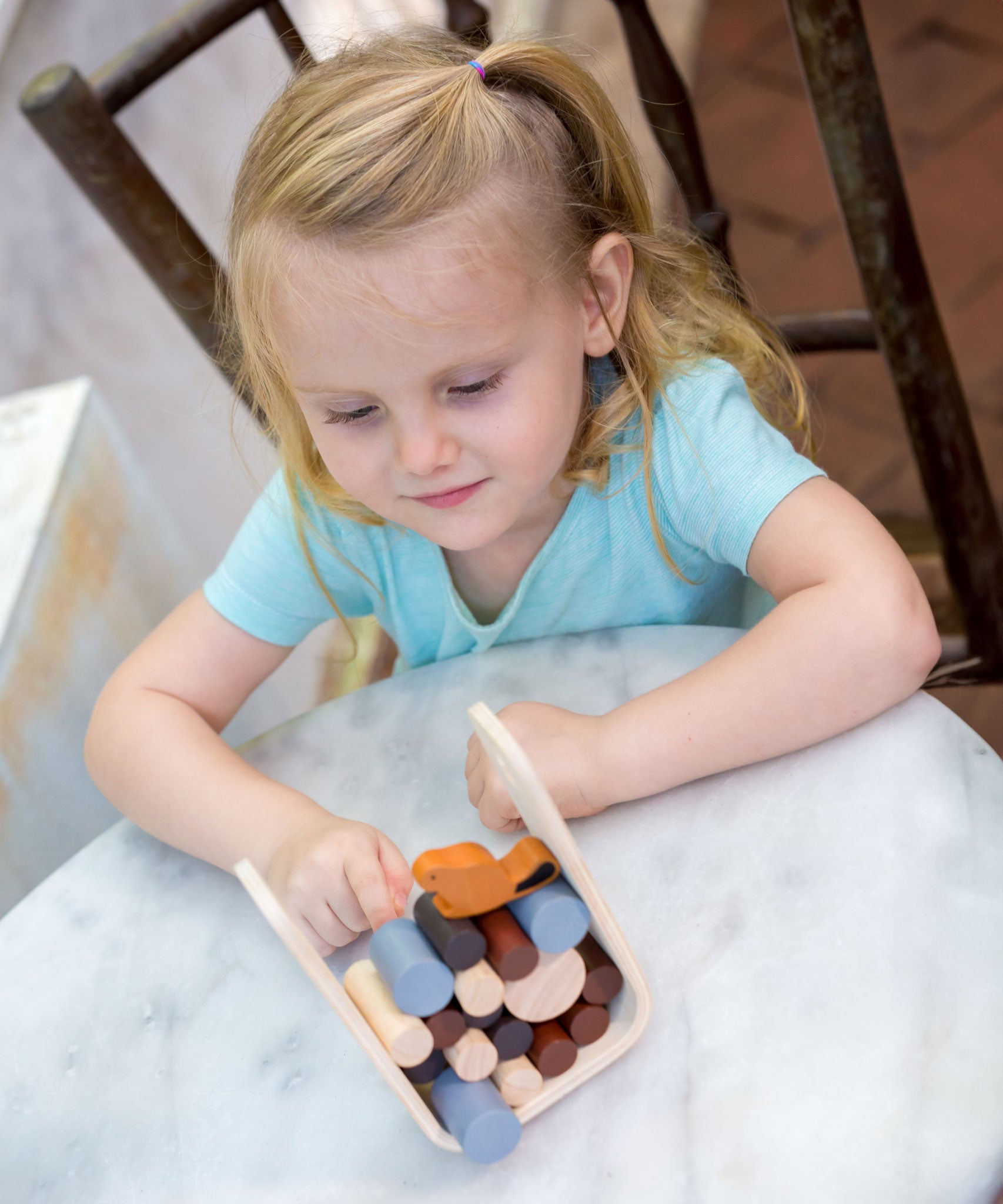 A child playing with the PlanToys Timber Tumble Game on white table. 