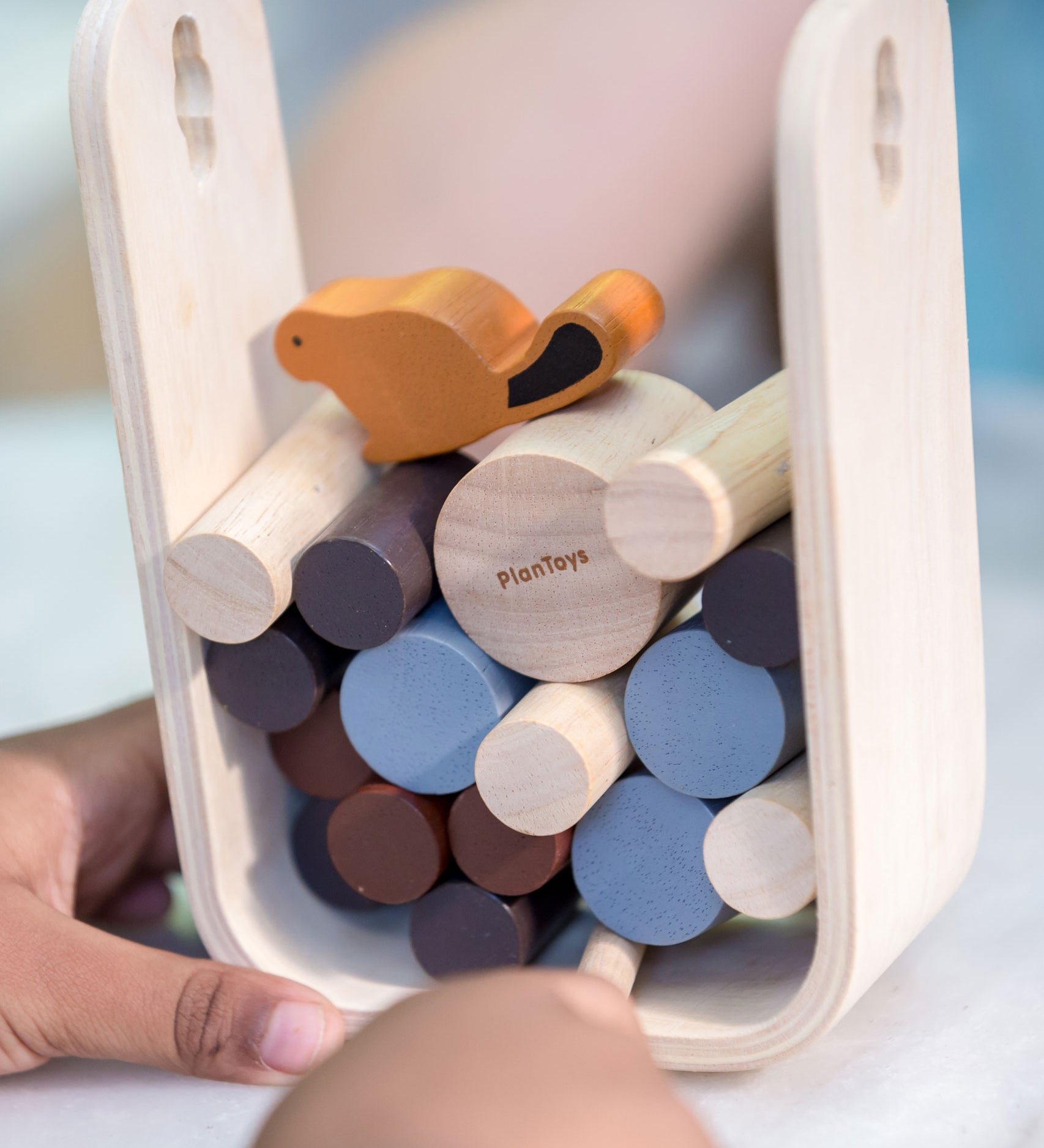 A close up of a child playing with the PlanToys Timber Tumble Game. 