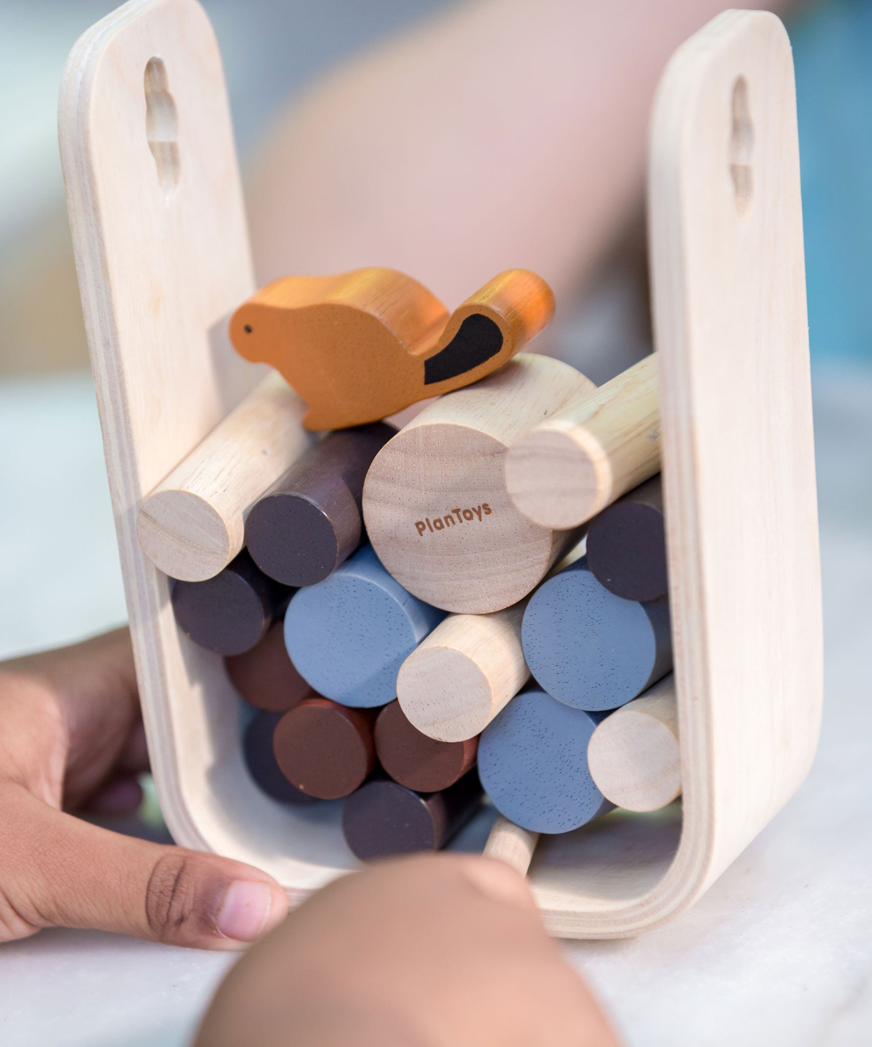 A close up of a child playing with the PlanToys Timber Tumble Game. 