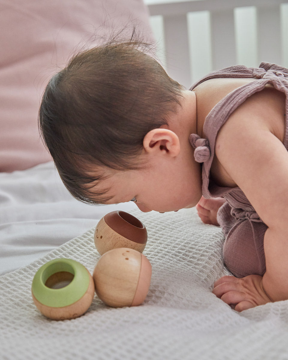 Close up of the PlanToys wooden sensory ball in a toddler's hand showing the fluffy texture inside