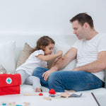 A child and adult playing with the PlanToys Doctor Set, the child is using the wooden toy injection. 