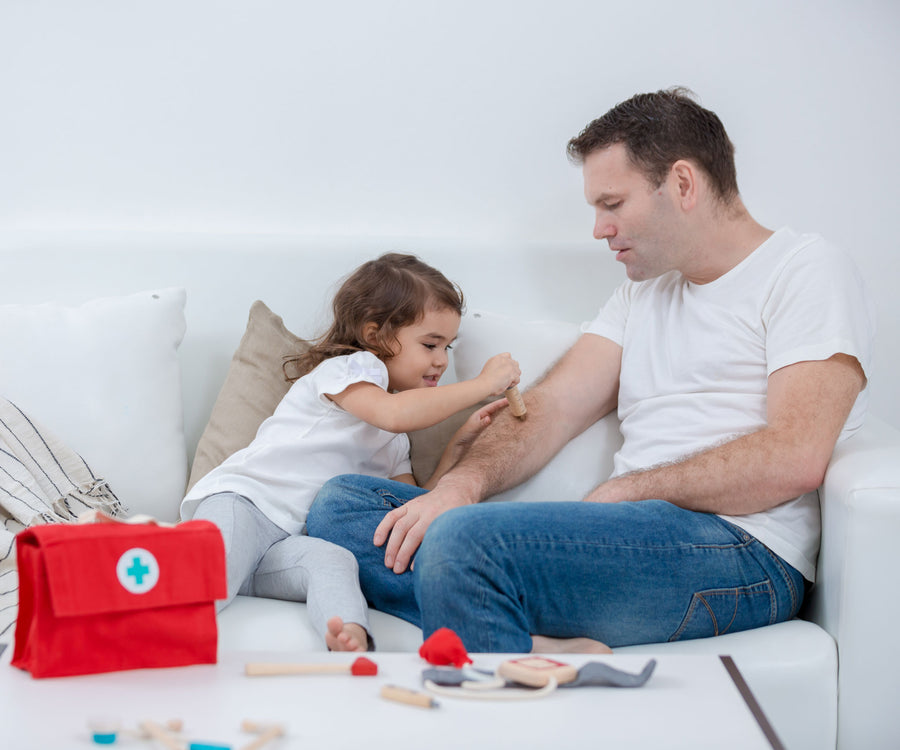 A child and adult playing with the PlanToys Doctor Set, the child is using the wooden toy injection. 