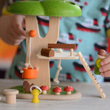 A close up of the PlanToys PlanWorld Tree House being played with by a child. The child's hand can be seen holding onto the little wooden doll figure. 