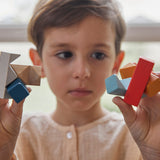 Close up of a child holding pieces of the PlanToys kids slotting block toy puzzle. 