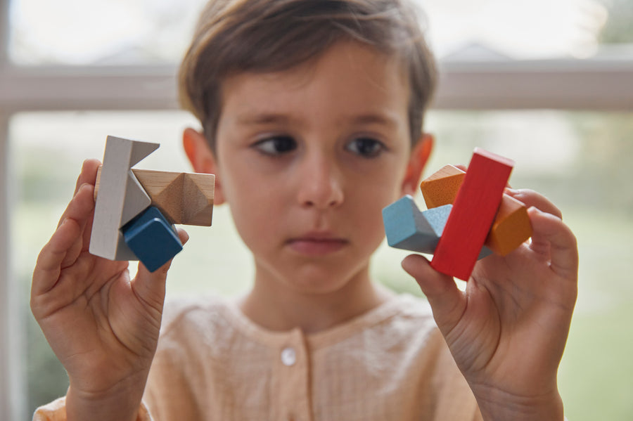 Close up of boy holding pieces of the PlanToys kids slotting block toy puzzle