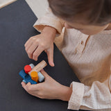 Close up of young child slotting together pieces from the PlanToys wooden logs puzzle on a black table