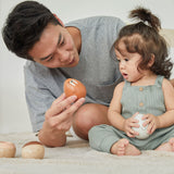 A young child and man sat on a fluffy carpet looking at the PlanToys plastic-free wobbly walrus toy.