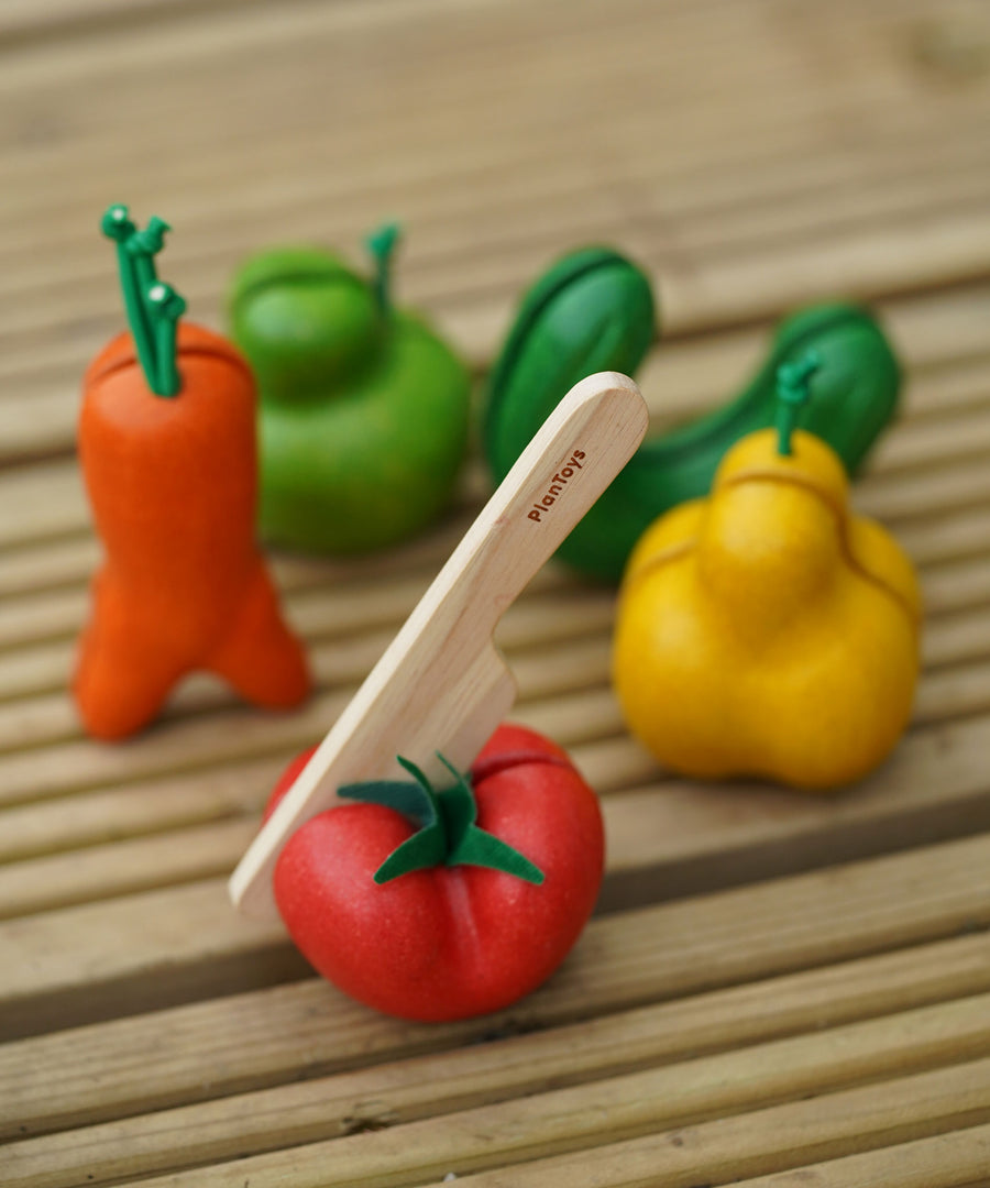 The PlanToys Wonky Fruit & Vegetables on a decking style surface. 