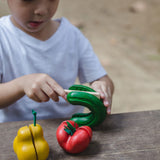 A child cutting up the toy cucumber from the PlanToys Wonky Fruit & Vegetables set. 