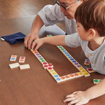 A child with an older man playing with the PlanToys wooden mood dominos game. 