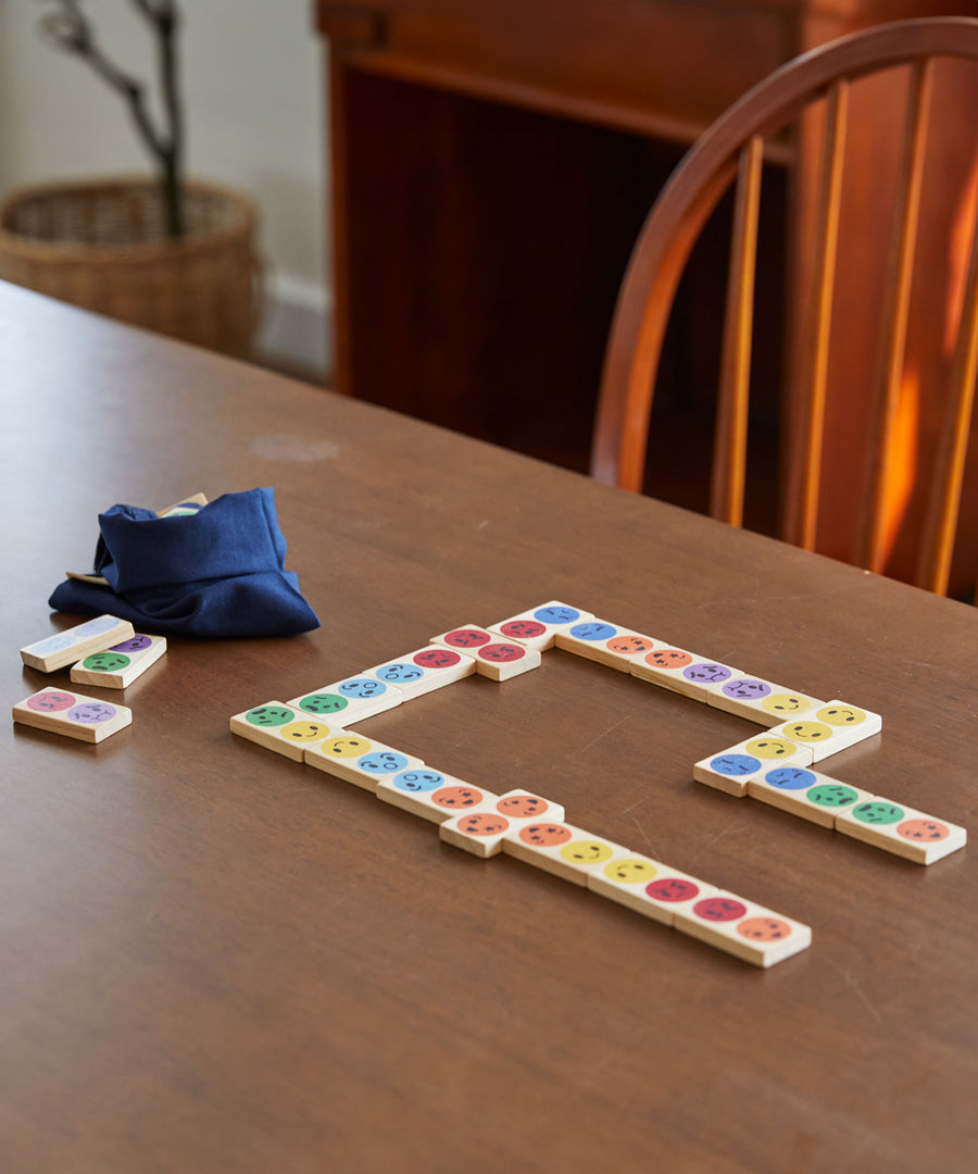 The PlanToys wooden mood dominos game set up on a wooden table.