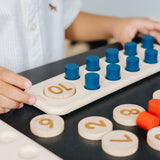 A close up of a child's hand playing with the PlanToys 10 Frame Number Game.