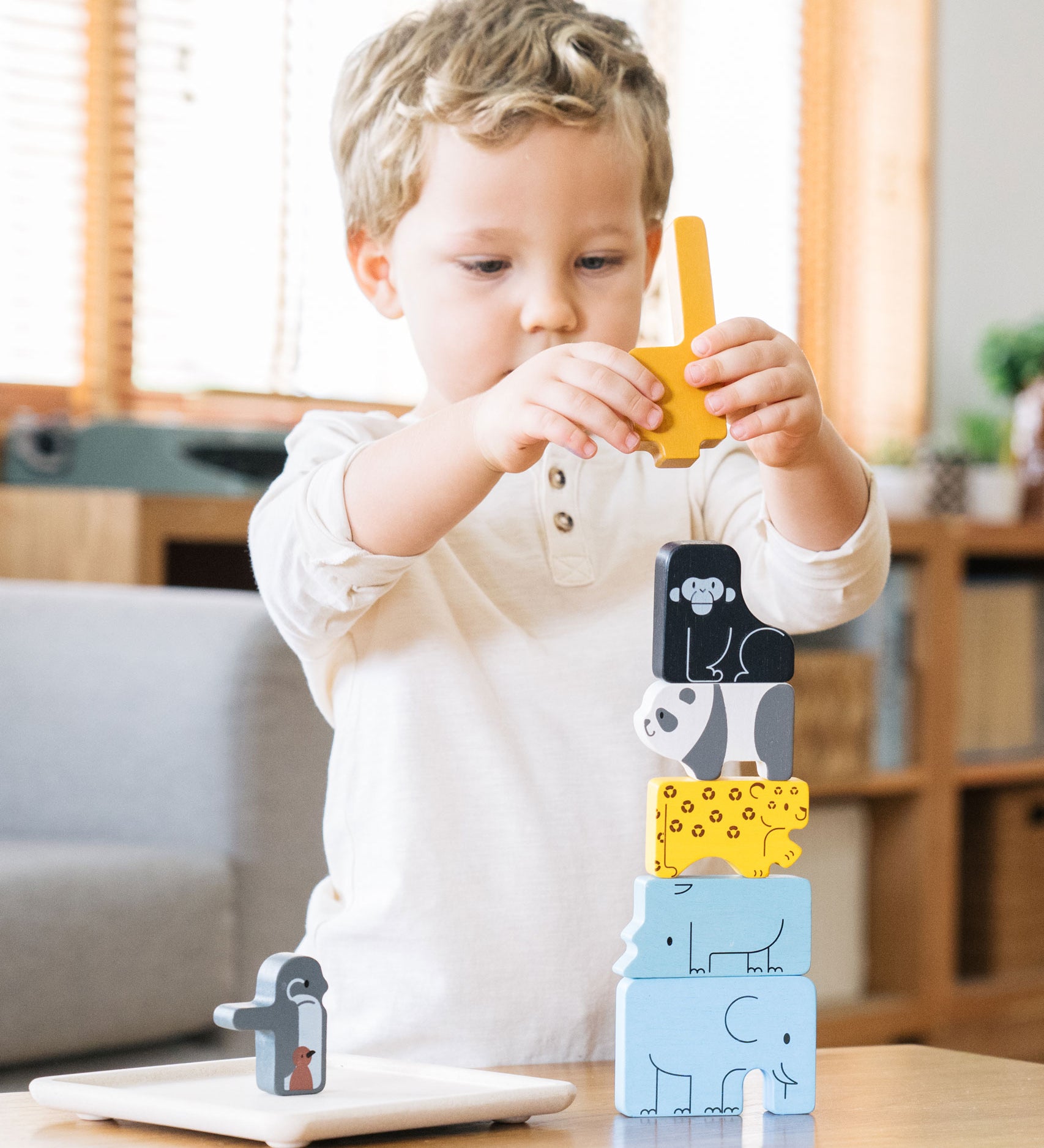 A child stacking the pieces from the Plan Toys Animal Puzzle Game
on the wooden base that comes with the game.