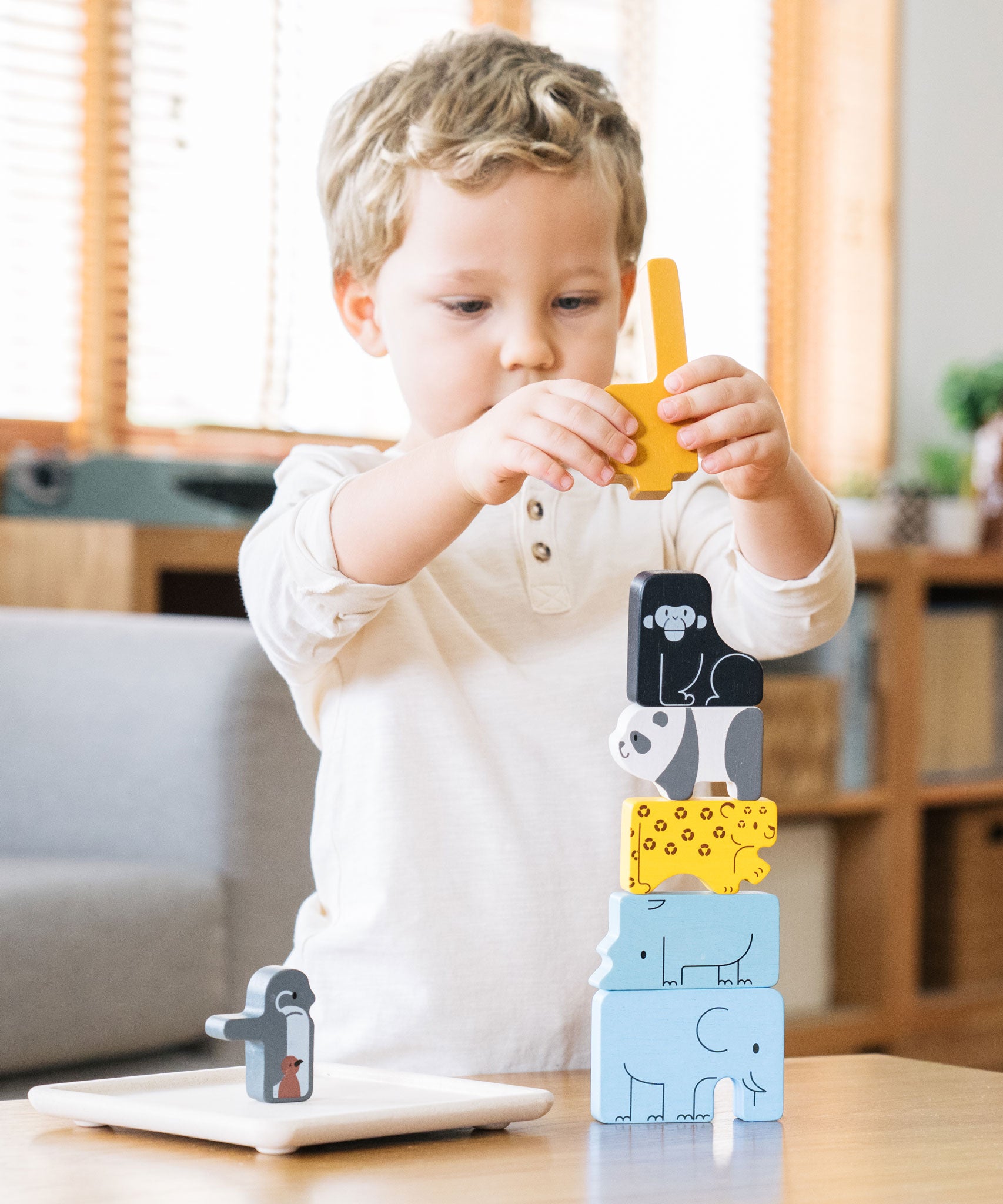 A child stacking the pieces from the Plan Toys Animal Puzzle Game
on the wooden base that comes with the game.