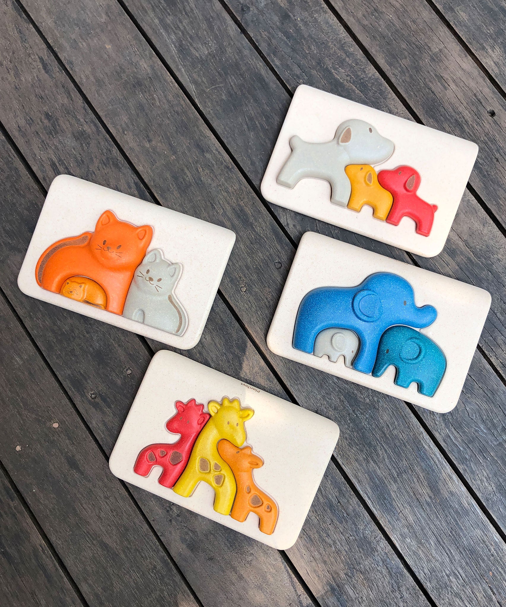 Four animal themed wooden puzzles from PlanToys on a wooden surface, dog, Cat, Elephant and giraffe. 