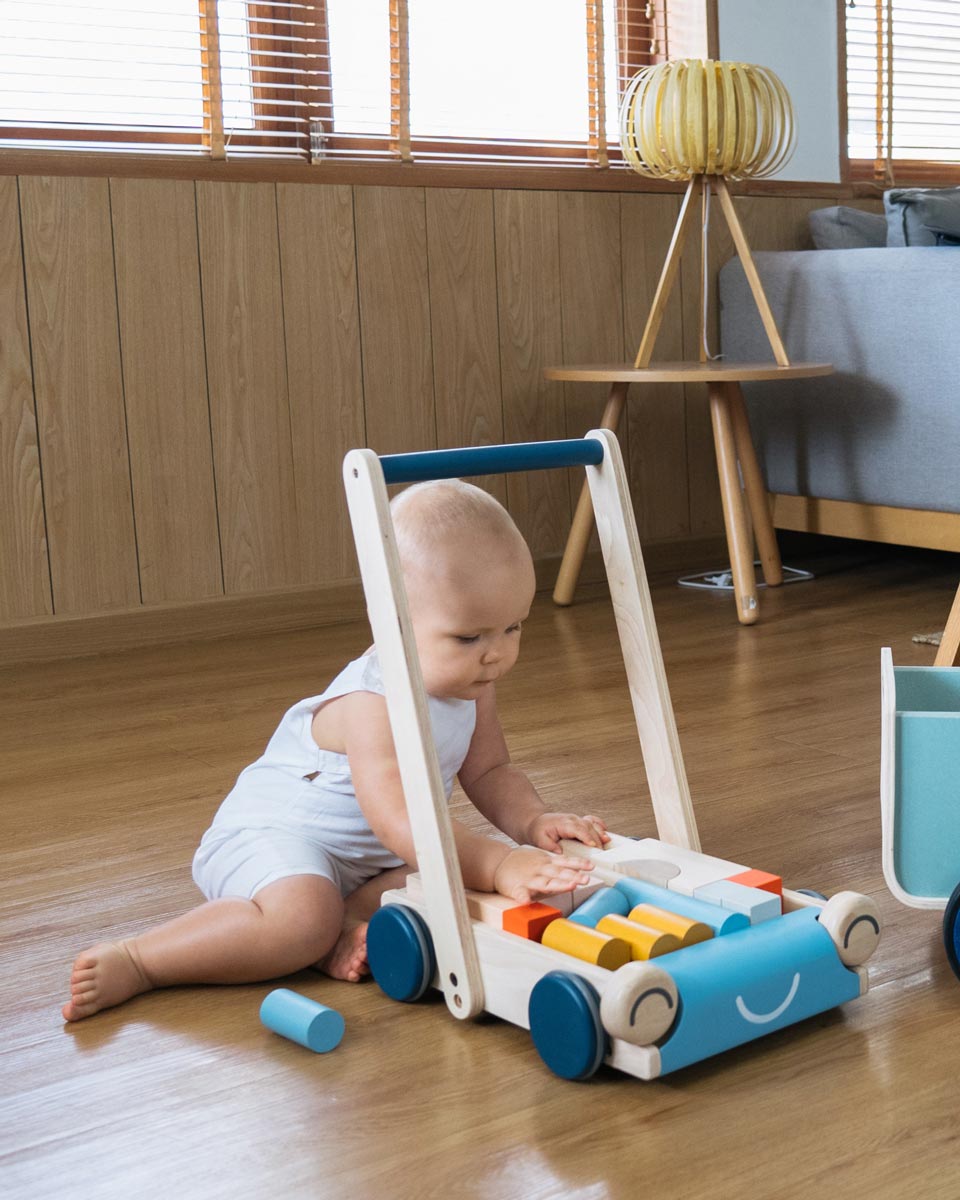 Young baby playing with wooden toy blocks in the Plan Toys orchard baby walker