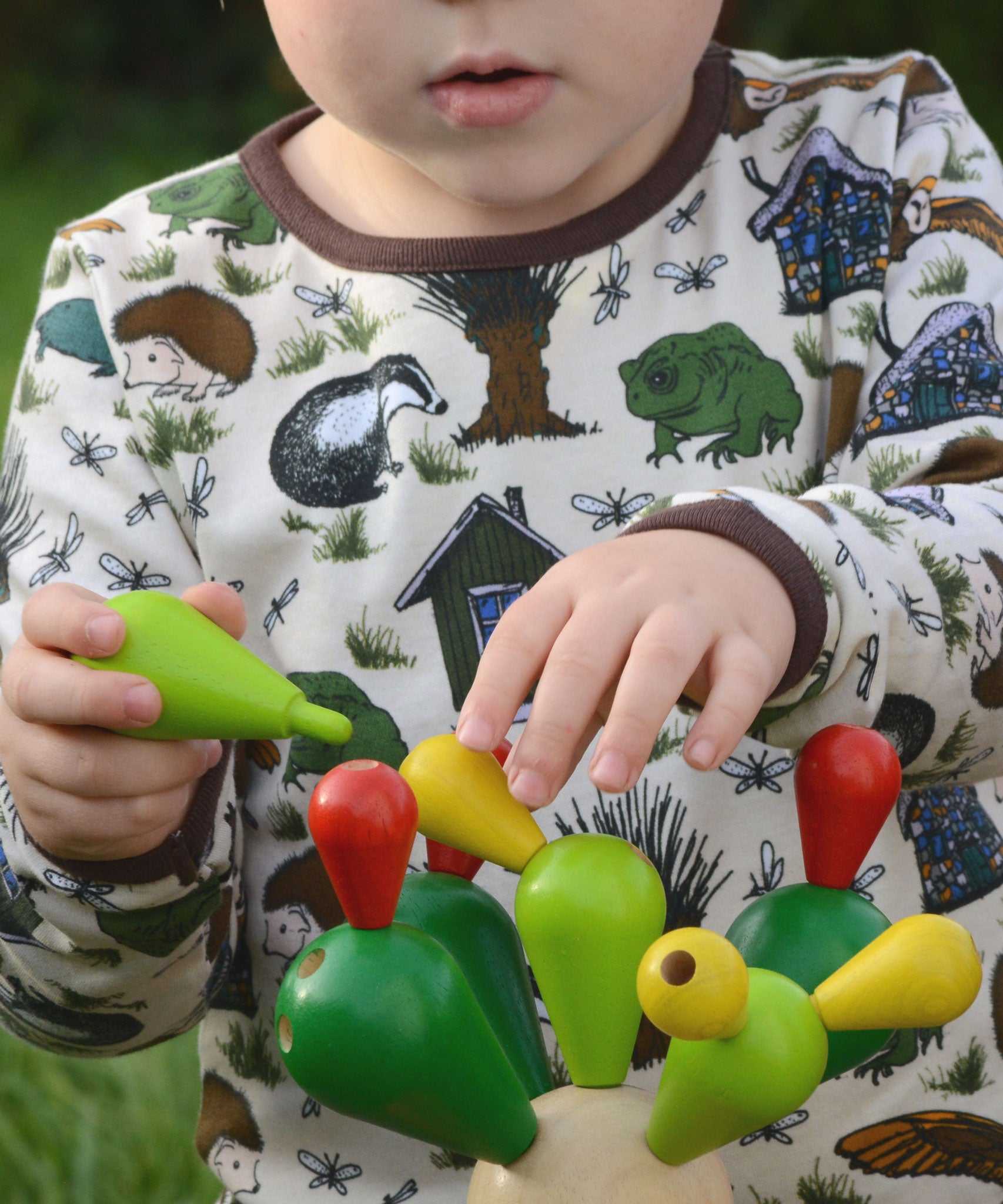 A close up of a child's hands playing with the  PlanToys Balancing Cactus.