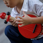 Ac lose up of a child playing with the PlanToys Wooden Toy Banjo.