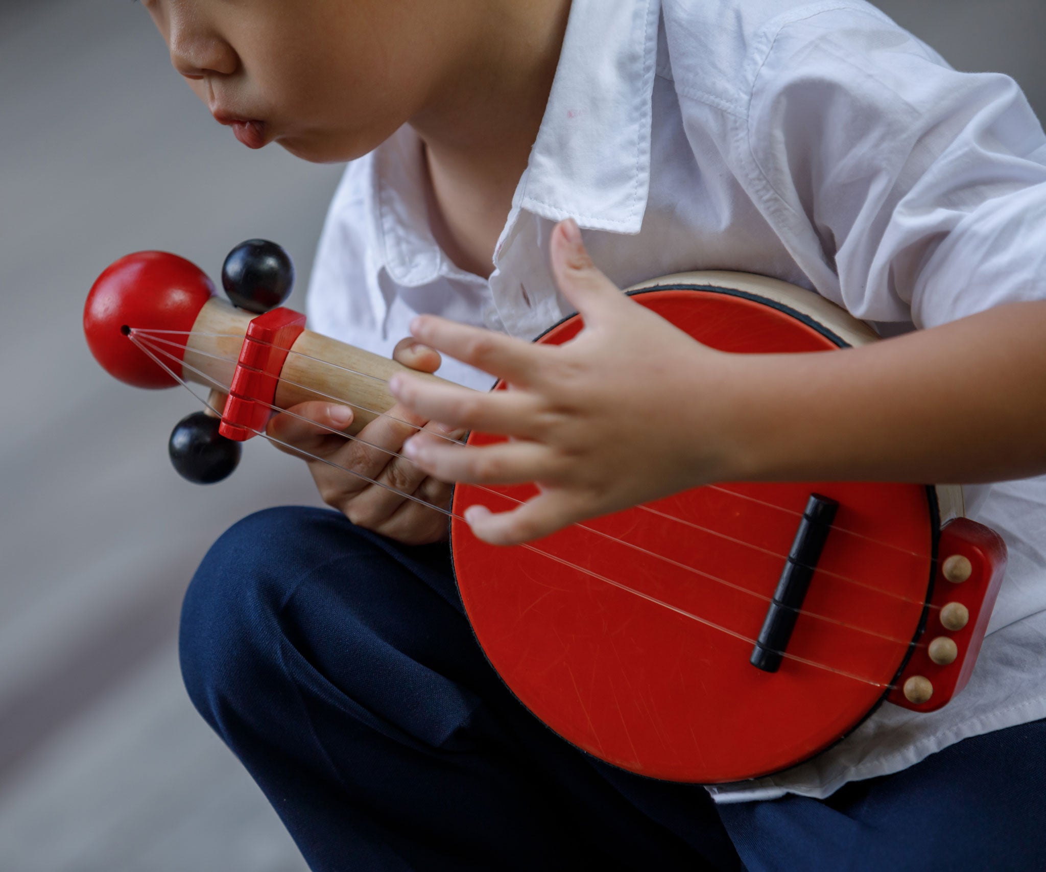 Ac lose up of a child playing with the PlanToys Wooden Toy Banjo.