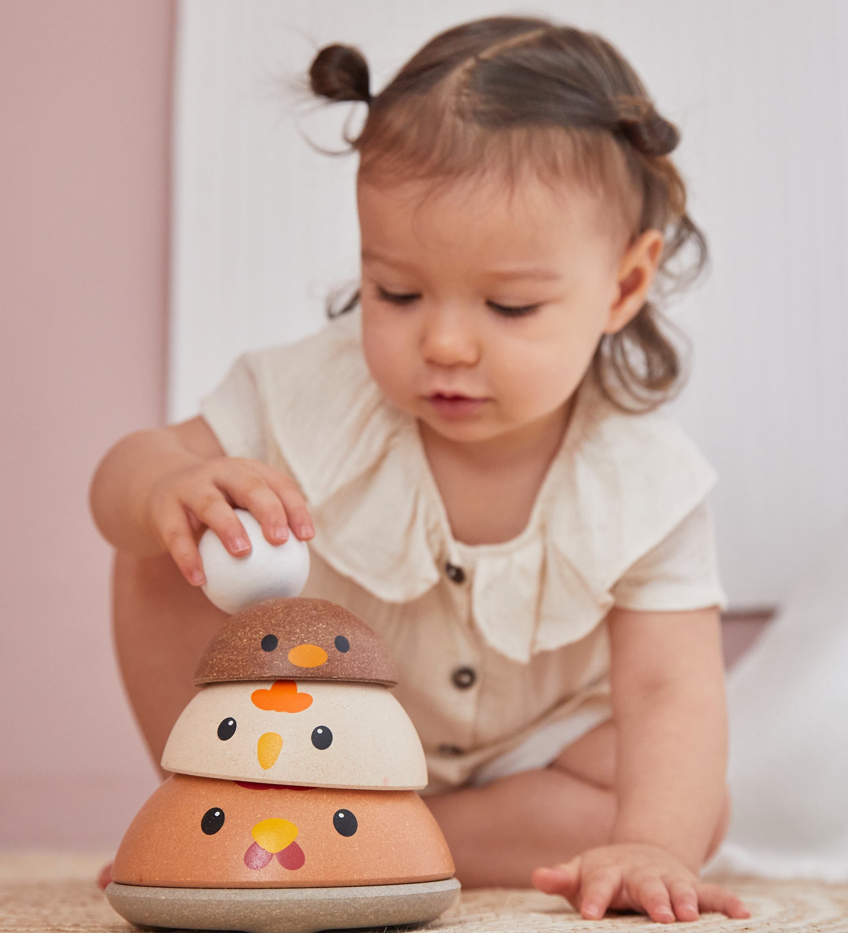 A child playing with the modern rustic colour PlanToys Chicken Nesting toy. 
