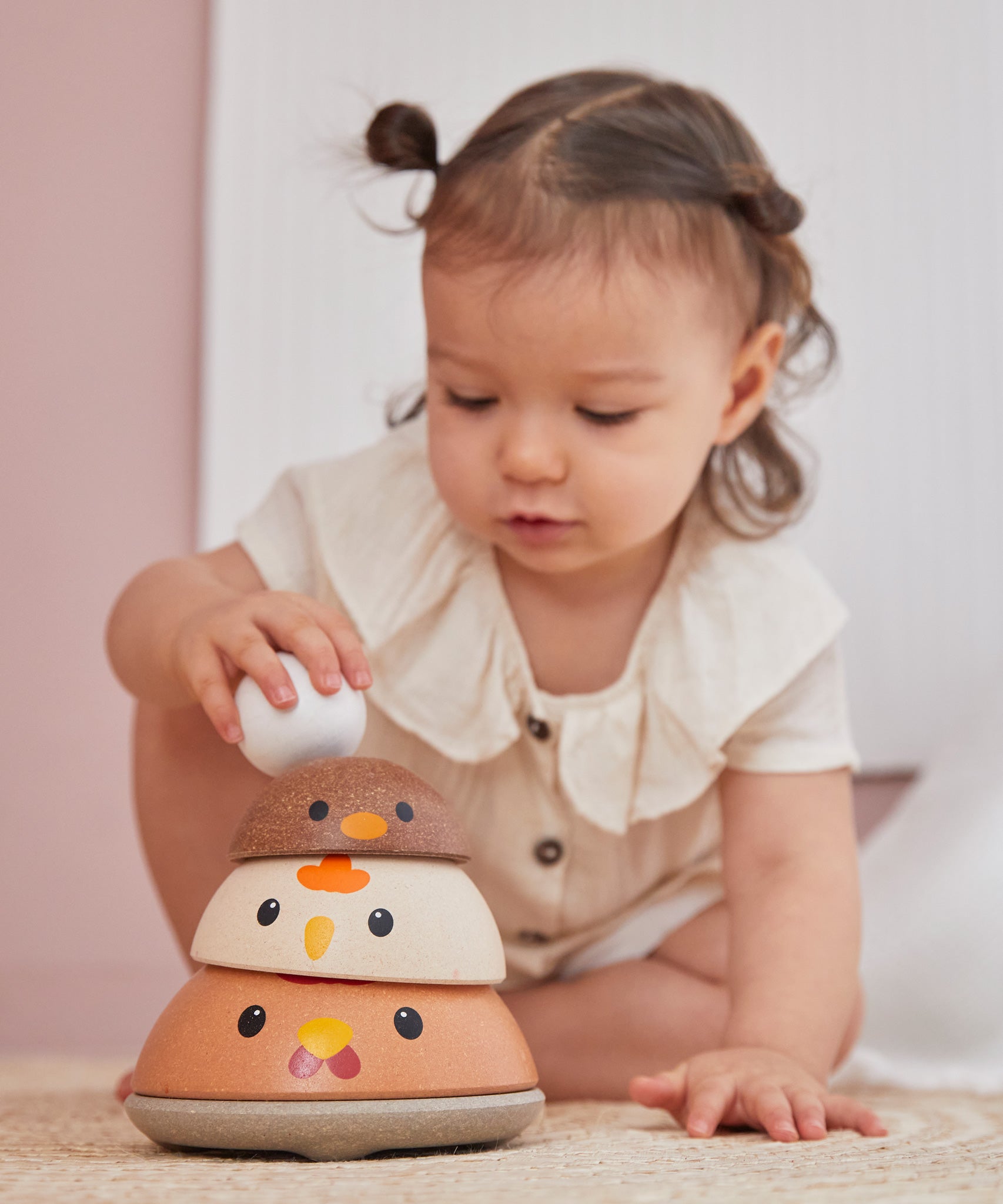 A child playing with the modern rustic colour PlanToys Chicken Nesting toy. 
