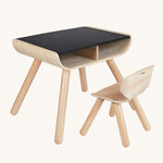 PlanToys wooden child's chair and desk on a plain background.