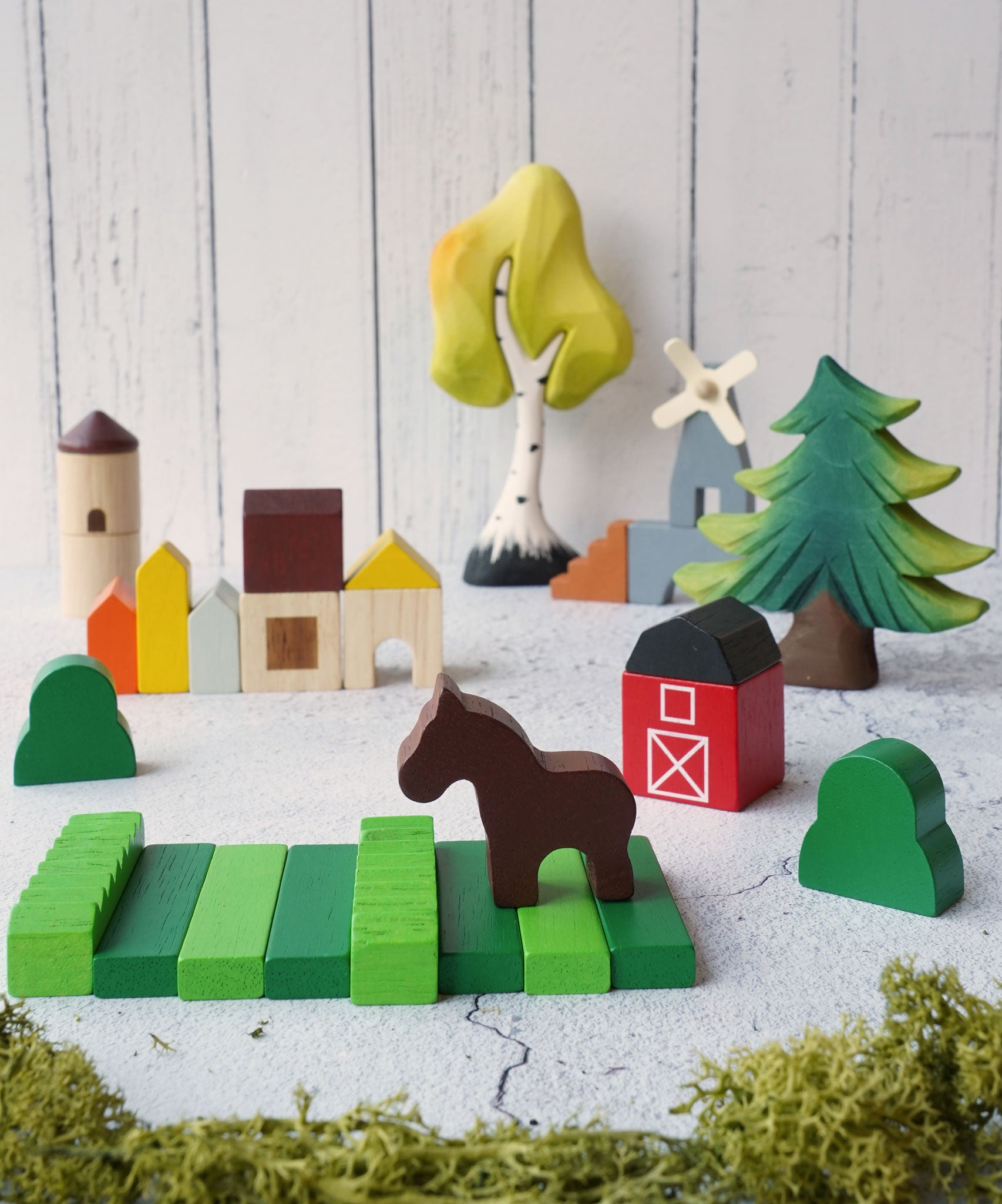 The PlanToys Wooden Country Blocks set up in a small world play set up, Bumbu trees can be seen in the background. 