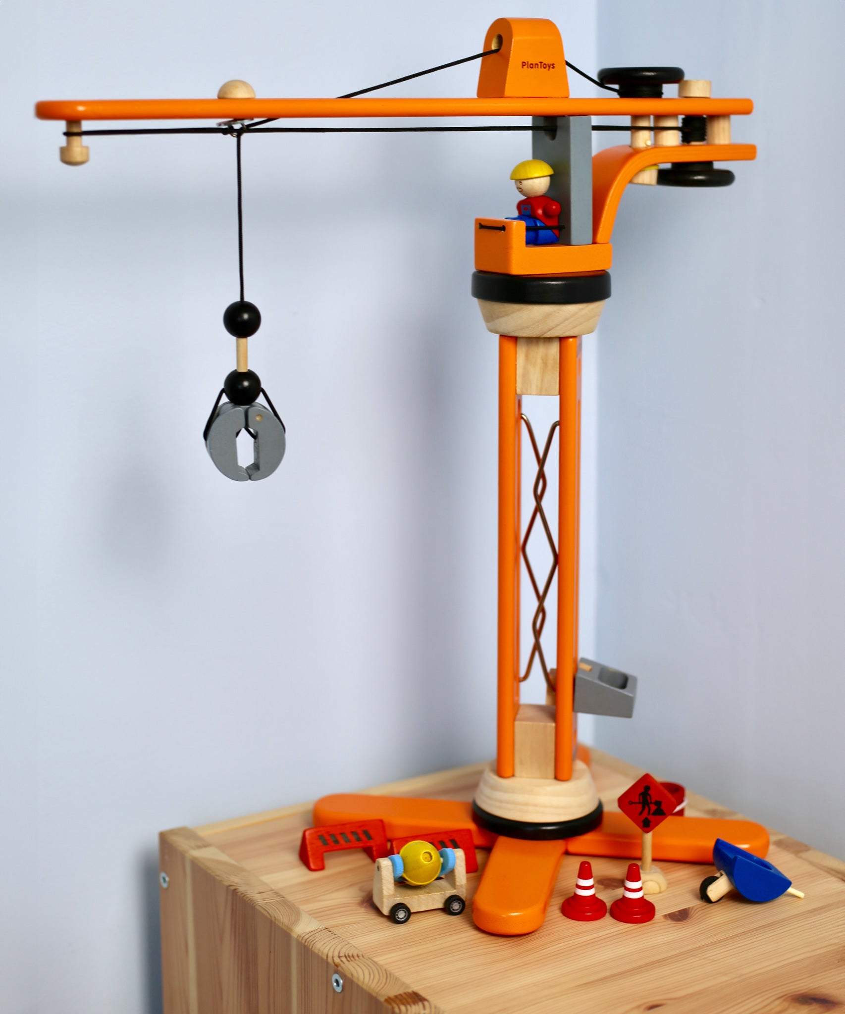 PlanToys PlanWorld Crane Set on a wooden shelf in front of a white wall. 