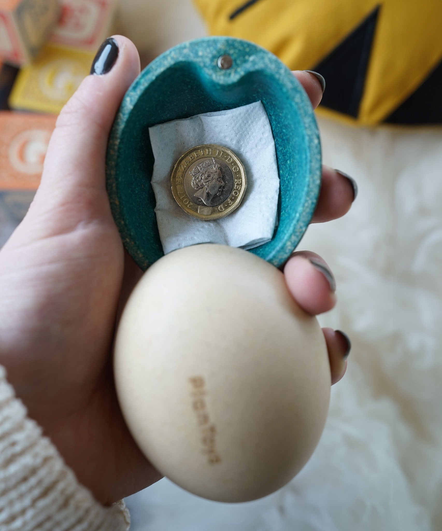 A blue coloured PlanToys surprise egg with a one pound coin placed inside. 