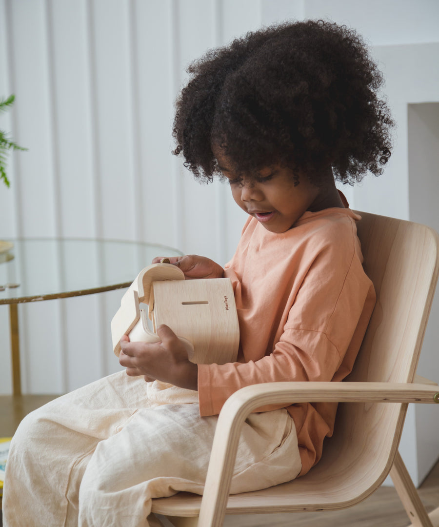 A child sitting down holding the PlanToys Elephant Money Bank.