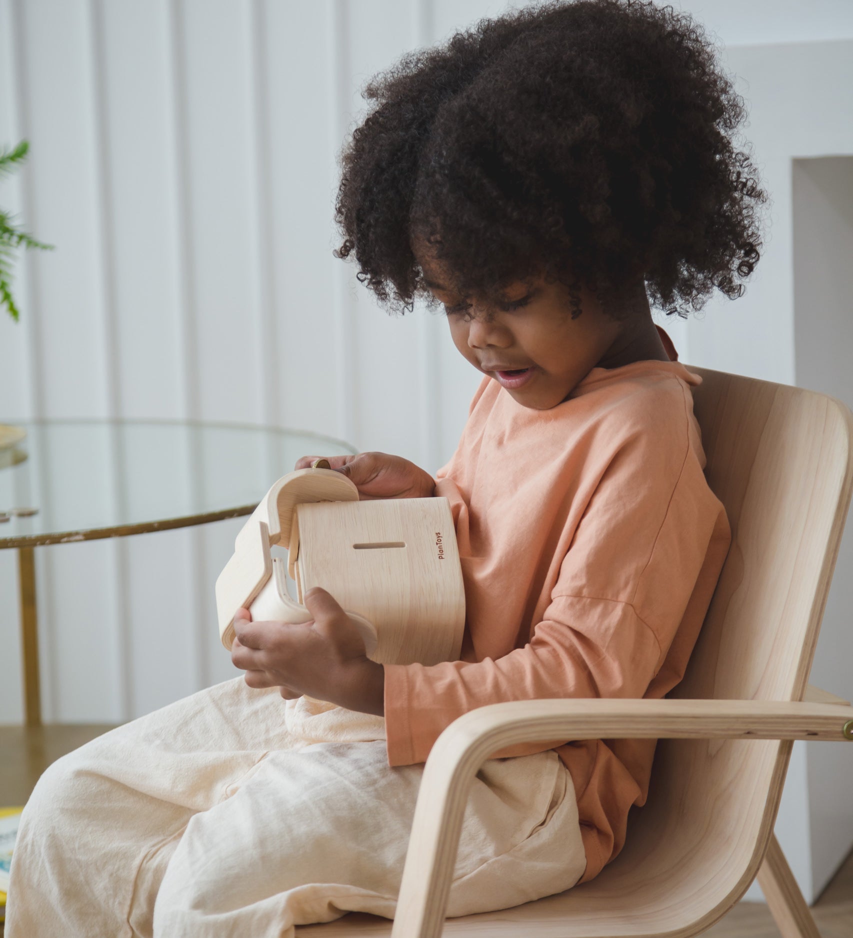 A child sitting down holding the PlanToys Elephant Money Bank.