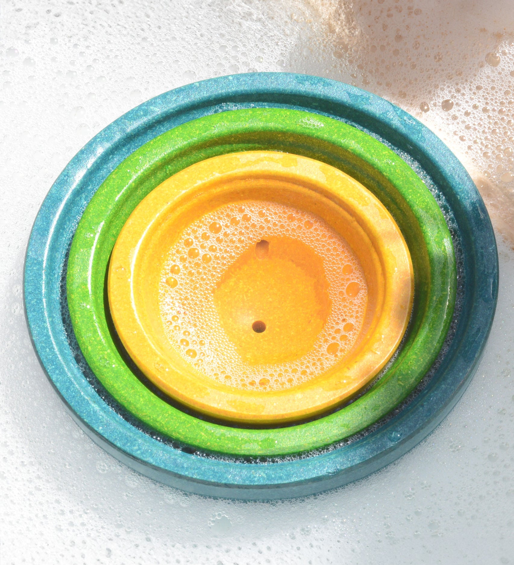 PlanToys Fountain Bowl Set nestled inside each other in a tub of bubbly water.