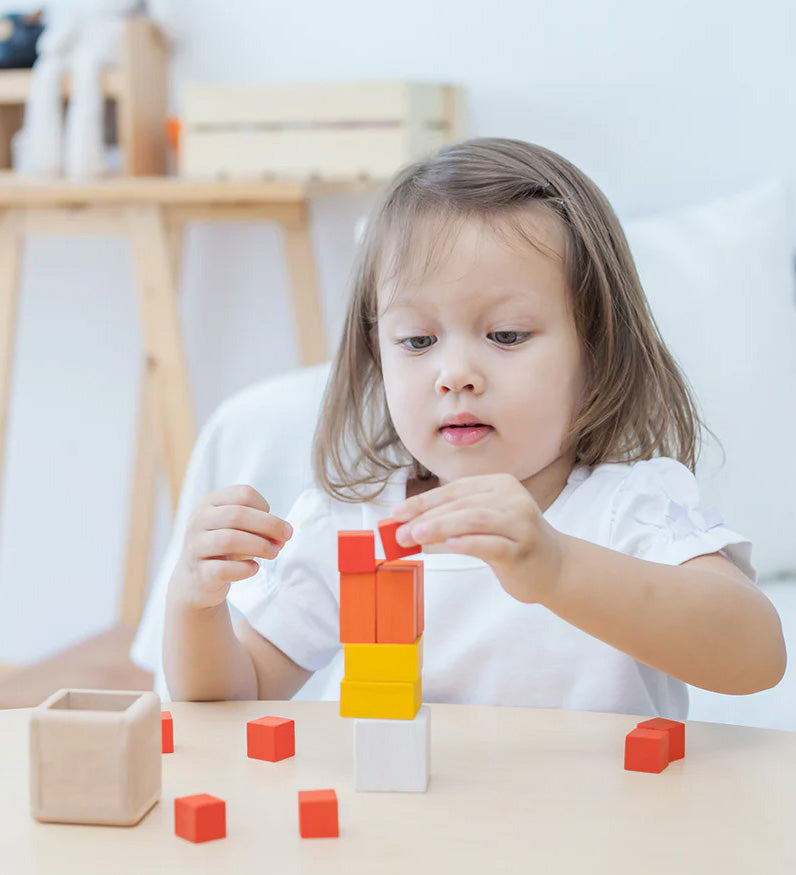 A child playing with the PlanToys Fractions Cubes. They are creating a stack. 