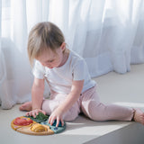 A child sitting on the floor playing with the PlanToys Marine Puzzle.