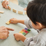 Close up of young boy putting down a piece of the PlanToys mood dominos set on a table