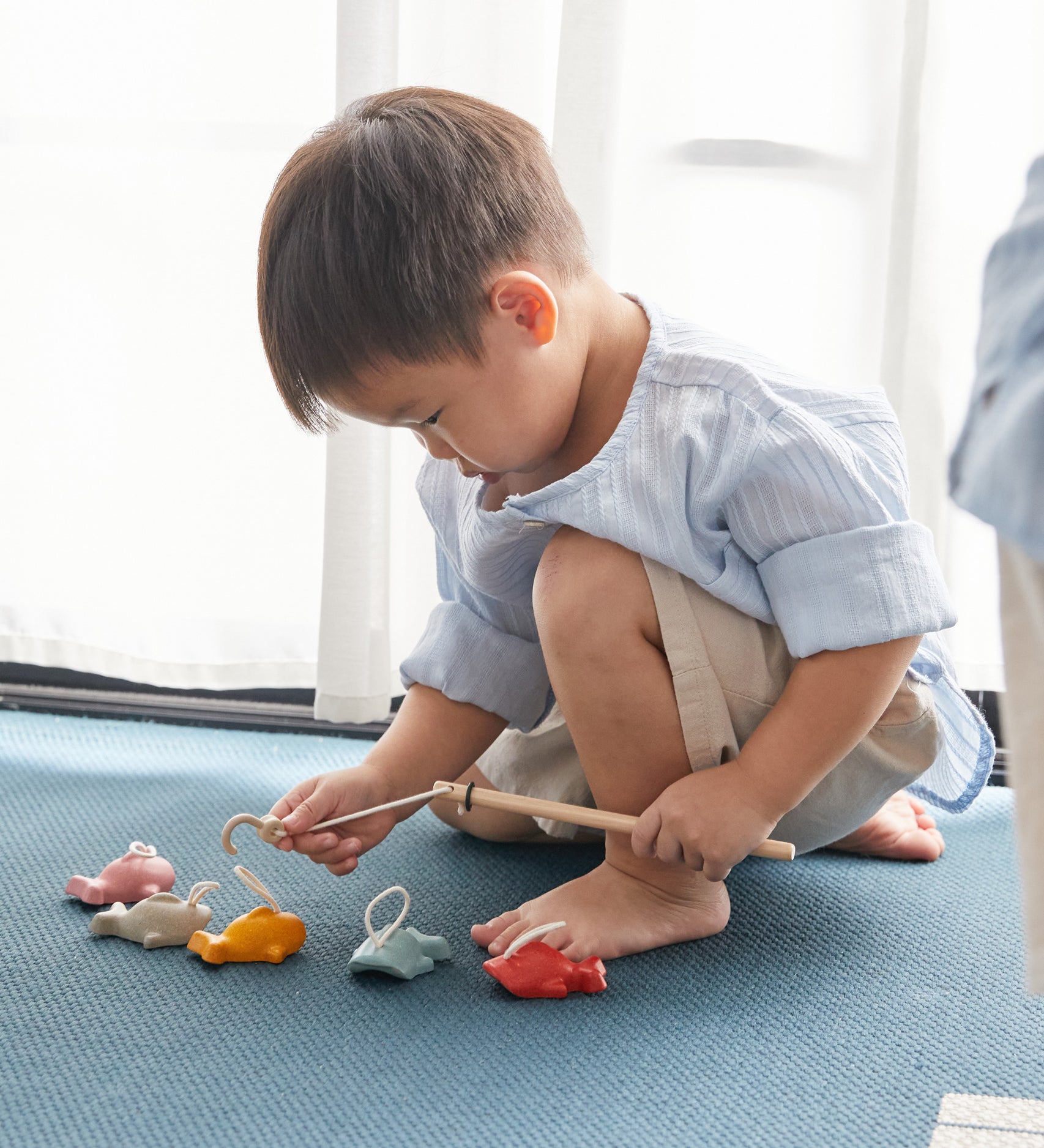 A child playing with the Plan Toys Fishing Game. 