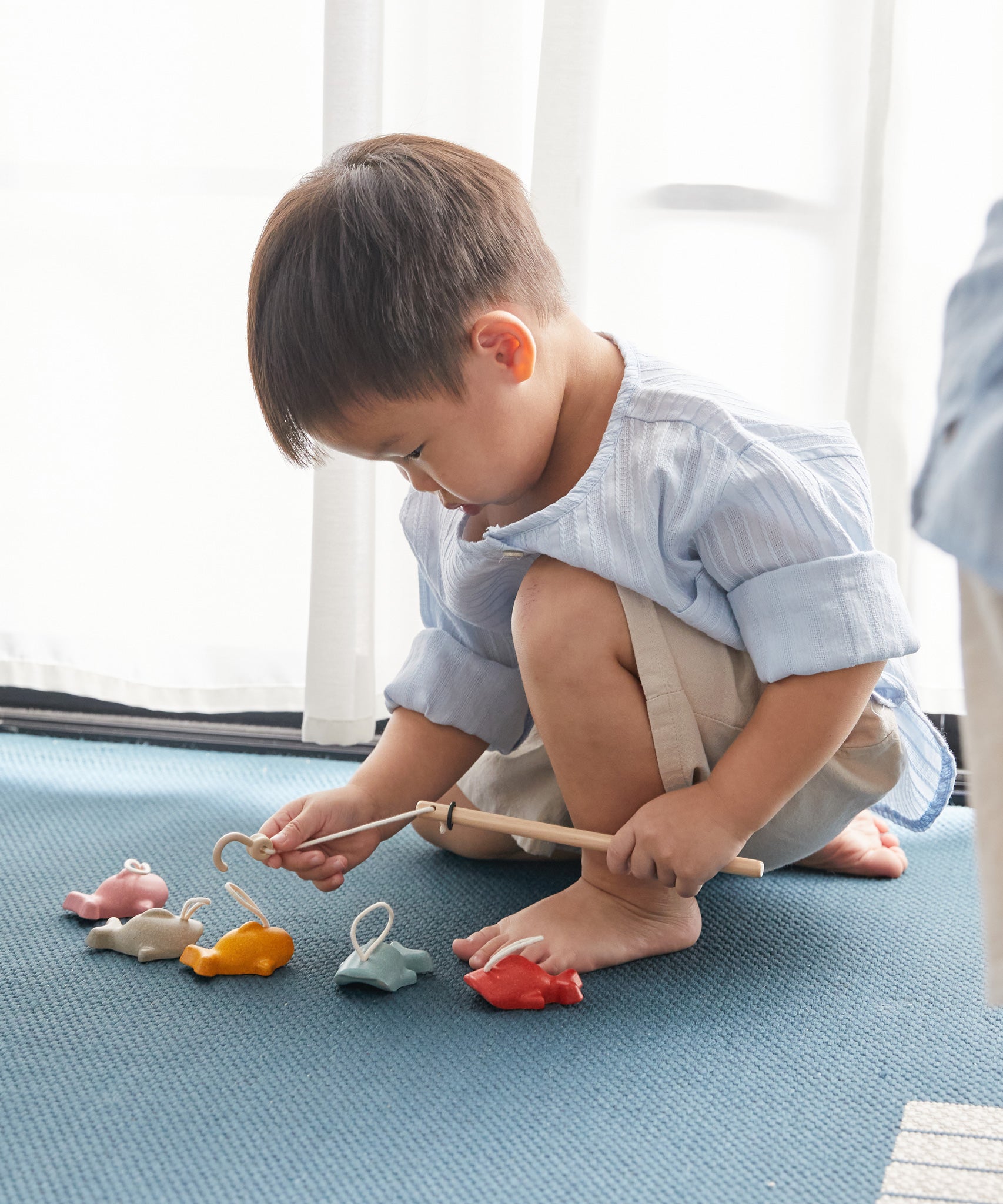 A child playing with the Plan Toys Fishing Game. 