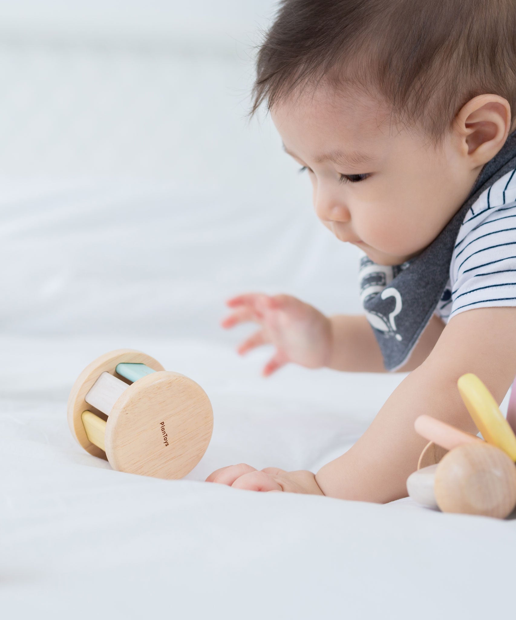 A baby crawling towards a PlanToys Pastel Roller. 