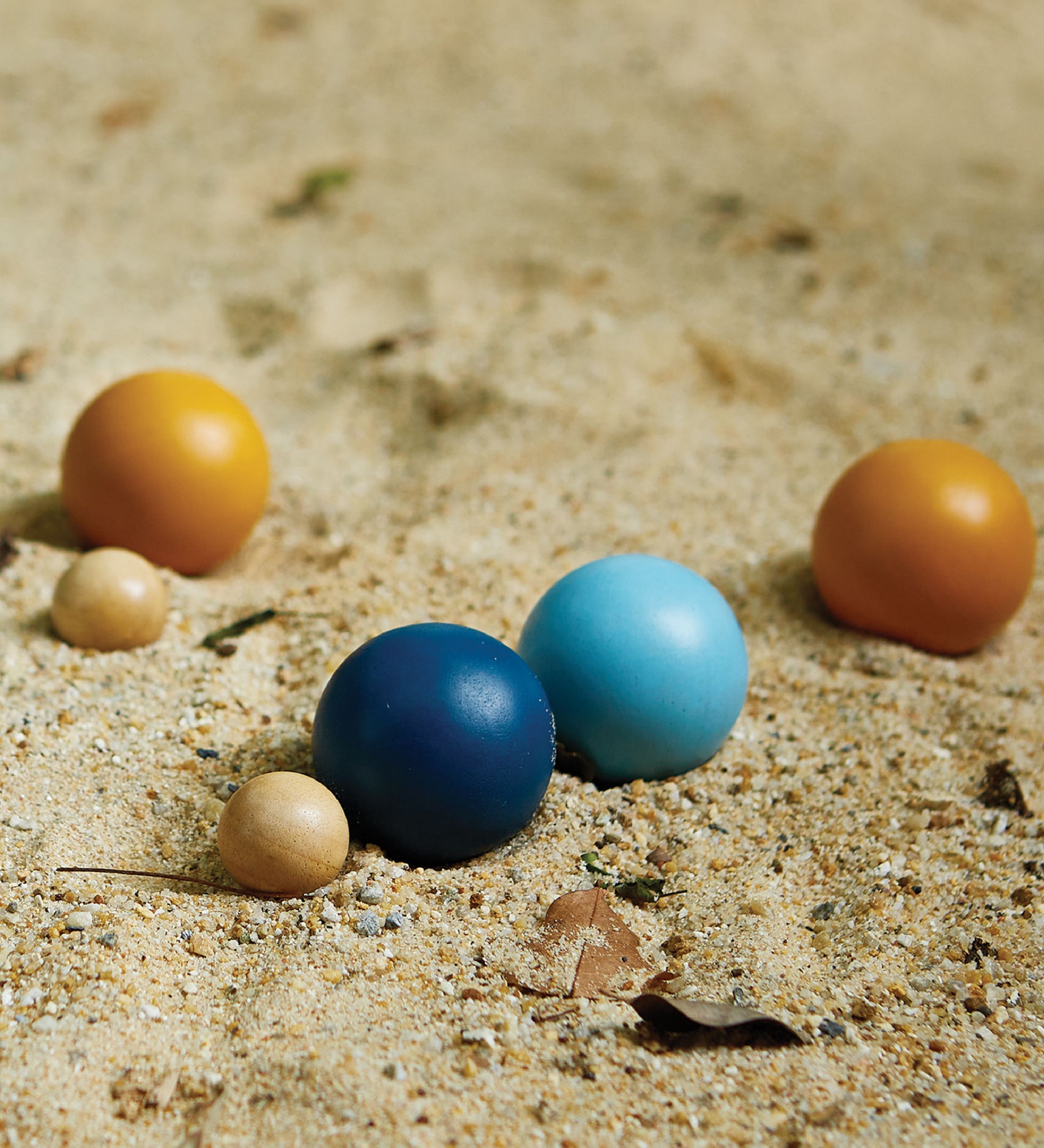 A close up of the Plan Toys plastic-free wooden petanque toy set on some sand.