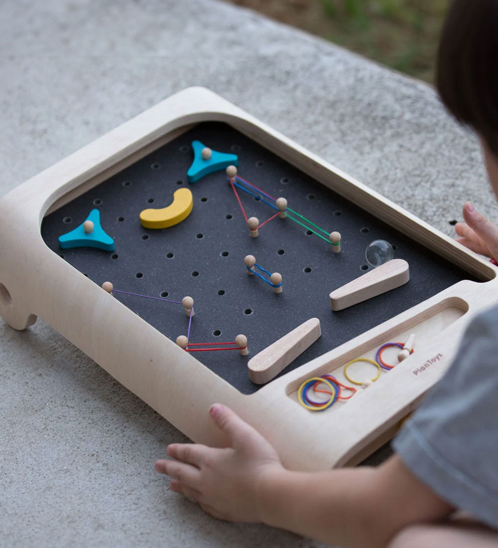 A close up of a child playing with the PlanToys pinball wooden toy game. 