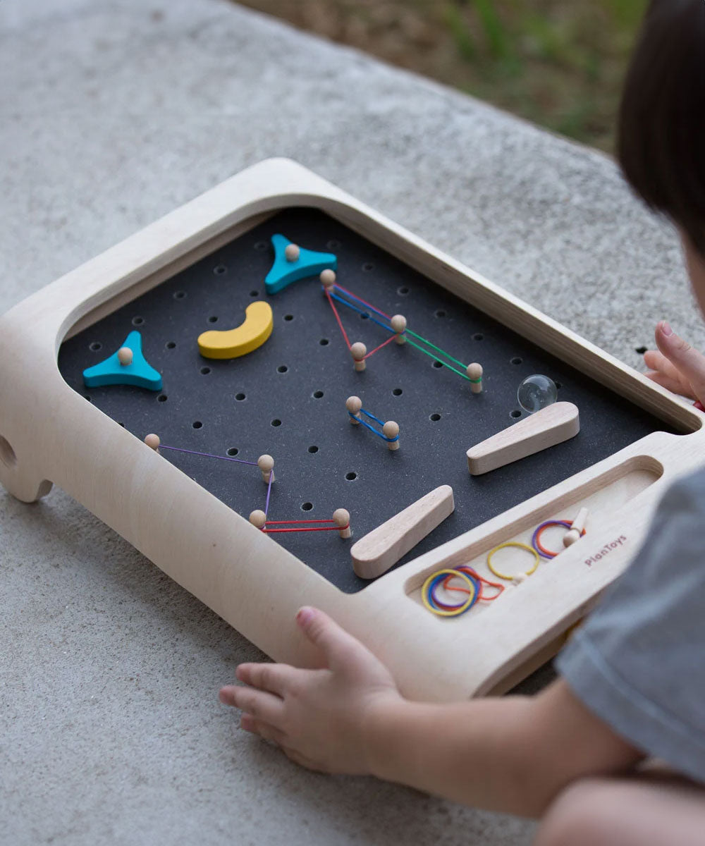 A close up of a child playing with the PlanToys pinball wooden toy game. 