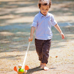 A child playing with the PlanToys Push Along Duck outdoors. 