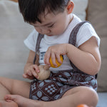 Child Concentrating on putting in Yellow PlanToys Wooden Nuts and Bolts Puzzle Ball bolt into a wooden Sphere