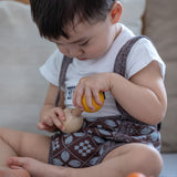 Child Concentrating on putting in Yellow PlanToys Wooden Nuts and Bolts Puzzle Ball bolt into a wooden Sphere