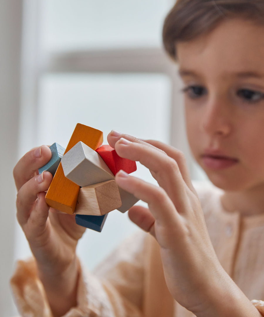 A close up of the PlanToys Waldorf toy block puzzle in a child's hands.