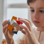 A close up of the PlanToys Waldorf toy block puzzle in a child's hands.